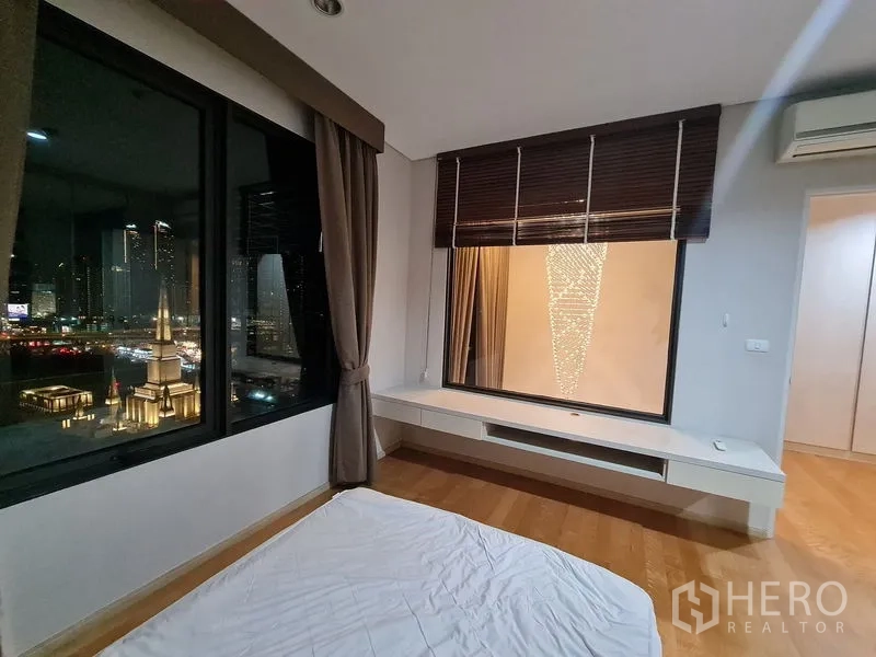 คอนโด ขายในRatchathewi, Bangkok - ห้องนอนพื้นไม้ หน้าต่างบานใหญ่พร้อมวิวเมืองกลางคืน และที่นั่งริมหน้าต่าง