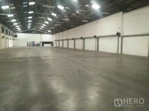货栈 出租在Khlong Luang, Pathum Thani - 仓库内部，高钢结构屋顶、抛光混凝土地面与墙面排风扇。