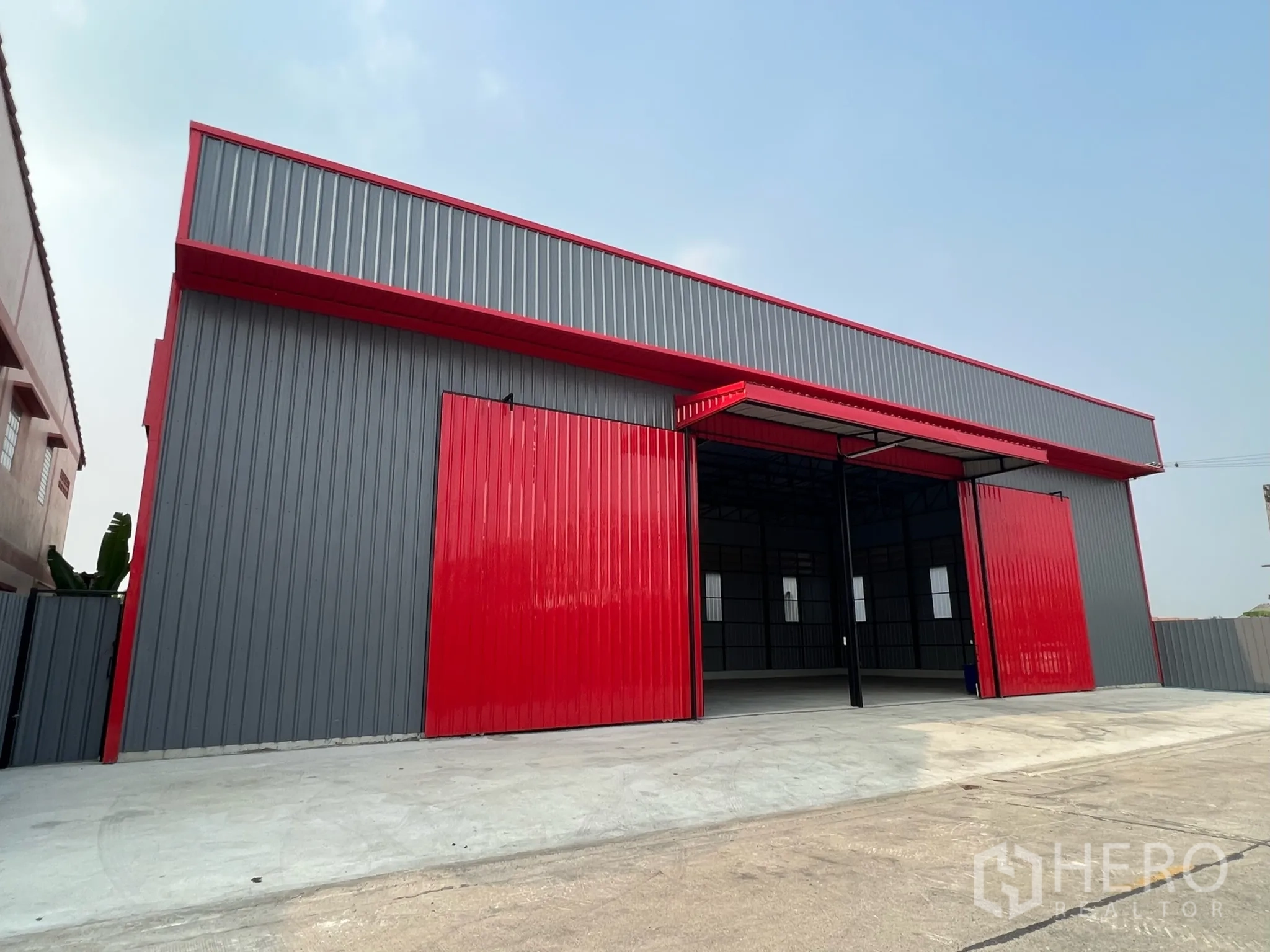 货栈 出租在Lam Luk Ka, Pathum Thani - 灰红配色仓库外立面，超大推拉门与前方装卸场地。