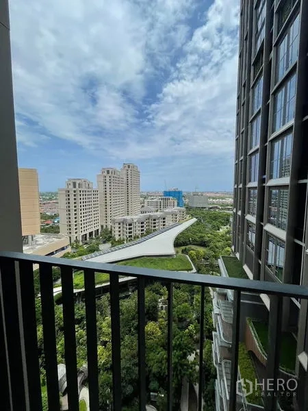 Condominium for rent in Samut Prakan - Balcony outlook across landscaped podium gardens, nearby towers and blue sky.