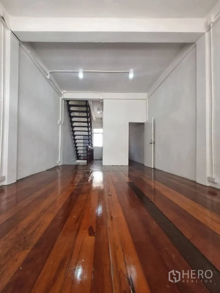 ตึกแถว for rent in Phra Khanong, Bangkok - ห้องชั้นบนพื้นไม้ขัดมัน ผนังสีขาว และบันไดด้านหลัง.