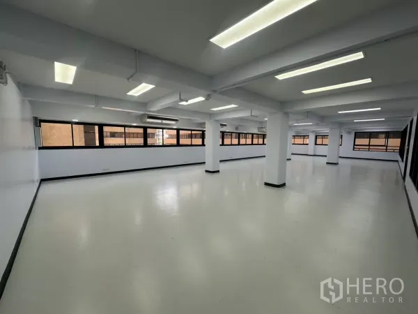 办公空间 出租 - 开放式办公室，白色地面与立柱，长条窗和明亮的LED天花灯。