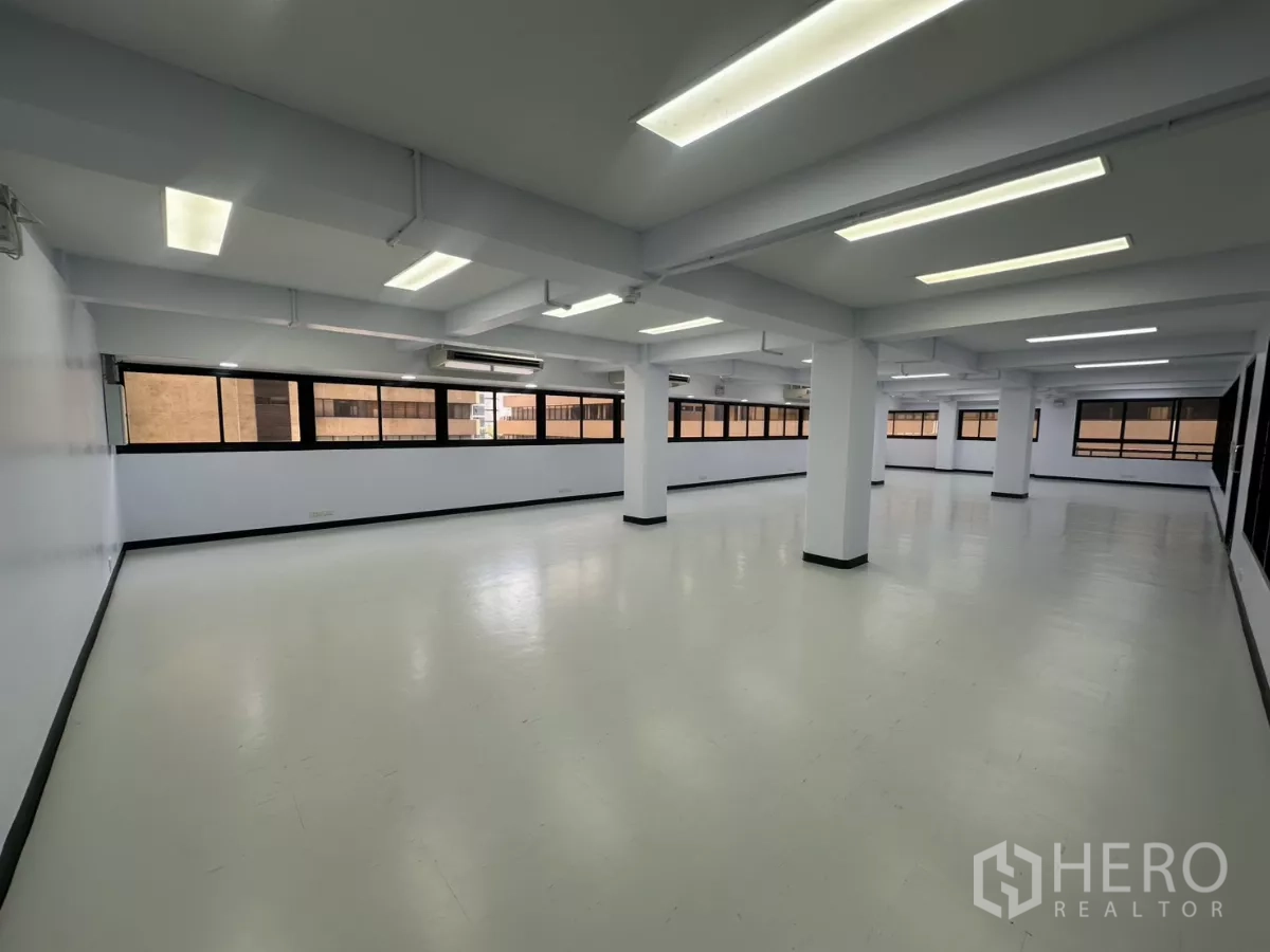 办公空间 出租 - 开放式办公室，白色地面与立柱，长条窗和明亮的LED天花灯。