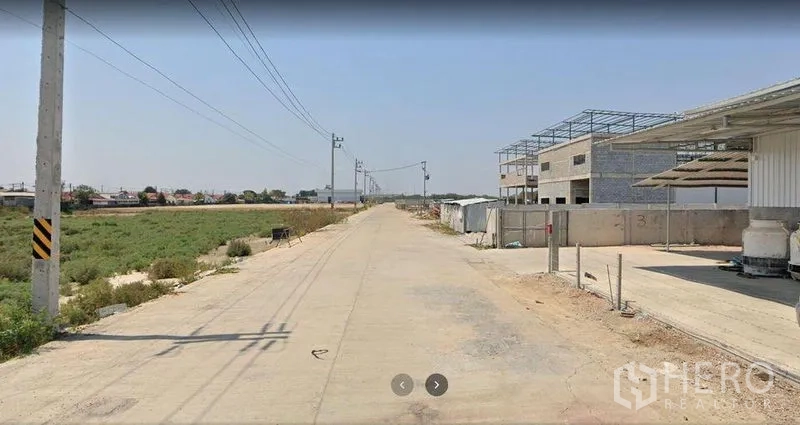 Factory for sale in Krathum Baen, Samut Sakhon - Concrete access road in an industrial area with power lines and nearby factories in Krathum Baen.