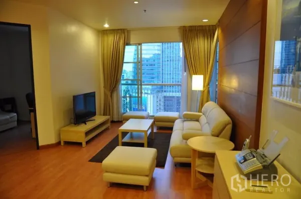 คอนโด ให้เช่าหรือขายในKhlong Toei, Bangkok - ห้องนั่งเล่นสว่าง โซฟาสีครีม ชุดทีวี พื้นไม้ และหน้าต่างระเบียงวิวเมือง