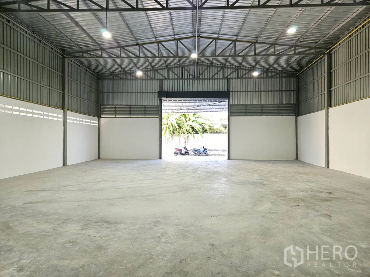 โกดัง for rent in Mueang Samut Prakan, Samut Prakan - มุมมองภายในไปยังประตูใหญ่พร้อมแสงสว่างและพื้นคอนกรีต