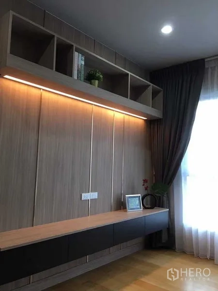 Condominium for sale in Khlong San, Bangkok - Wood-panelled feature wall with under-shelf LED lighting and window drapes.