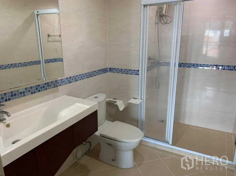 公寓 出租在Bang Rak, Bangkok - 浴室视角展示洗手台、镜子与滑门淋浴间。