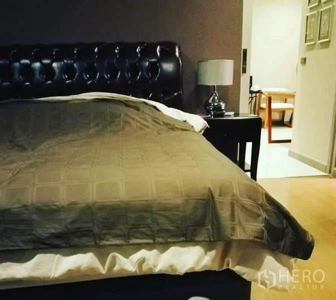 公寓 出售在Bang Rak, Bangkok - 卧室配软包皮革床头与床头灯，木地板。