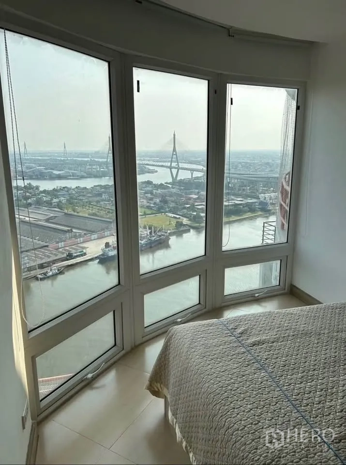 Condominium for rent or sale in Yan Nawa, Bangkok - Corner bedroom with curved bay windows framing river and Bhumibol Bridge views.