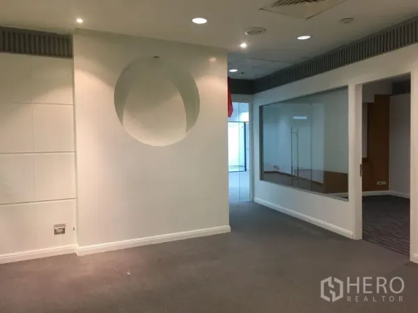 办公空间 出租在Chatuchak, Bangkok - 接待区，圆形墙面装饰，地毯地面，旁边为玻璃隔断会议室。