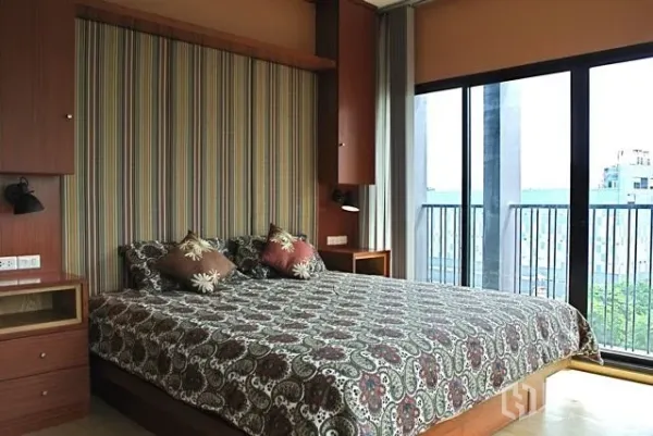 คอนโด ให้เช่าในWatthana, Bangkok - ห้องนอนพร้อมหน้าต่างบานใหญ่เปิดสู่ระเบียง มองเห็นวิวเมืองและผนังตกแต่งลายริ้ว