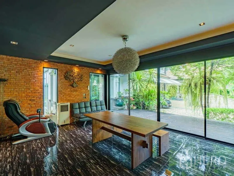 Detached House for sale in Suan Luang, Bangkok - Multi-purpose room with exposed brick wall, large wooden table and sliding glass doors to the patio.