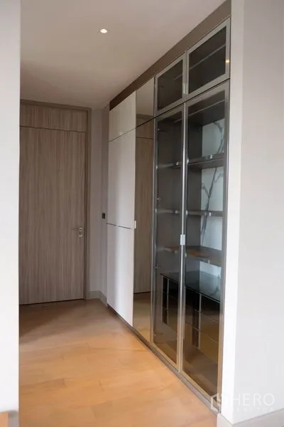 บ้าน ให้เช่าในWatthana, Bangkok - โถงทางเดินพร้อมตู้โชว์บานกระจกและตู้เก็บของสีขาว พื้นไม้สีอ่อน