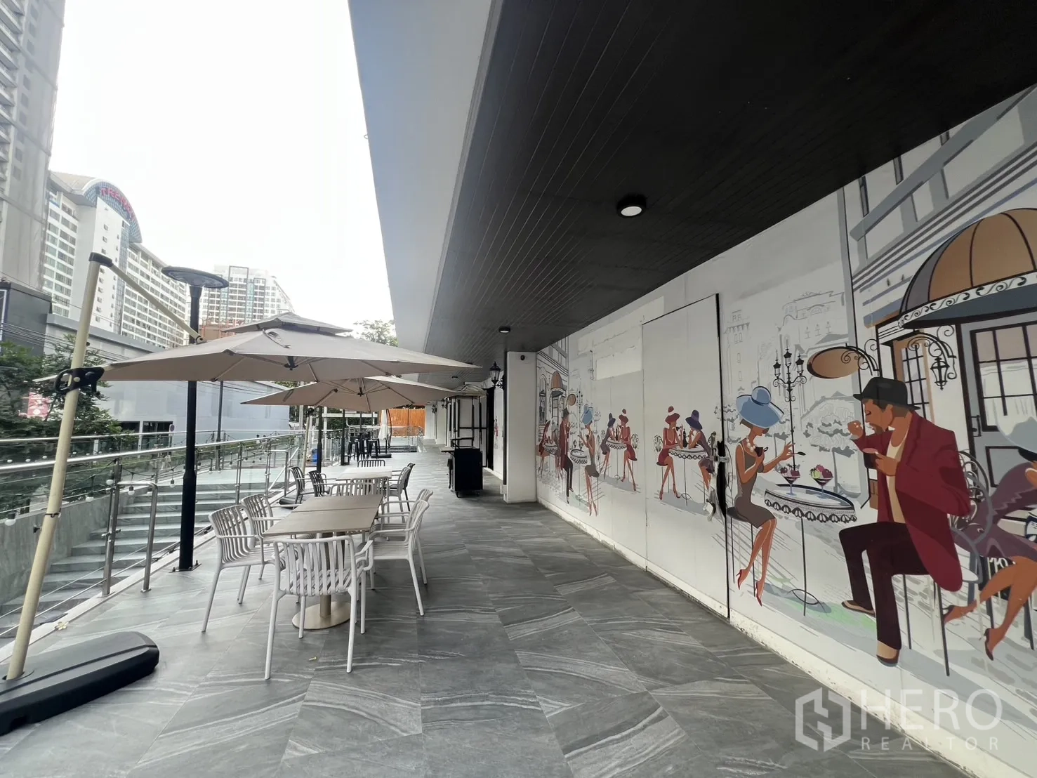 พื้นที่ขายปลีก ให้เช่า - ทางเดินโปรเมนาดพร้อมภาพวาดสไตล์คาเฟ่ โต๊ะกลางแจ้ง และร่ม ขนาบราวกระจก