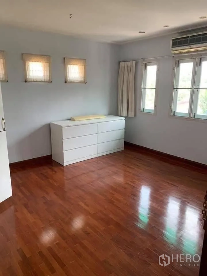 联排别墅 for rent in Watthana, Bangkok - 明亮卧室，实木地板、抽屉柜、窗户与空调。