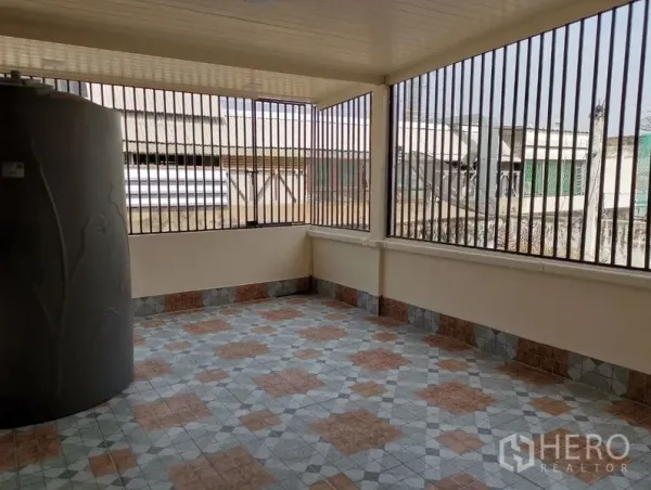 Townhouse for rent in Watthana, Bangkok - Covered rooftop terrace with patterned tiles, metal safety grills, and a water tank.