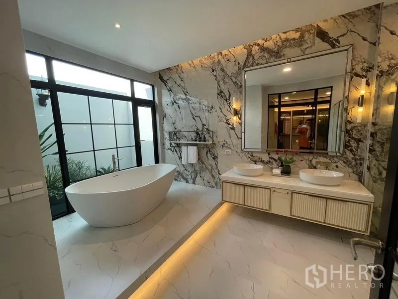 บ้าน ให้เช่าหรือขายในSaphan Sung, Bangkok - ห้องน้ำหรู อ่างอาบน้ำเดี่ยว ผนังลายหินอ่อน และเคาน์เตอร์อ่างคู่กระจกบานใหญ่