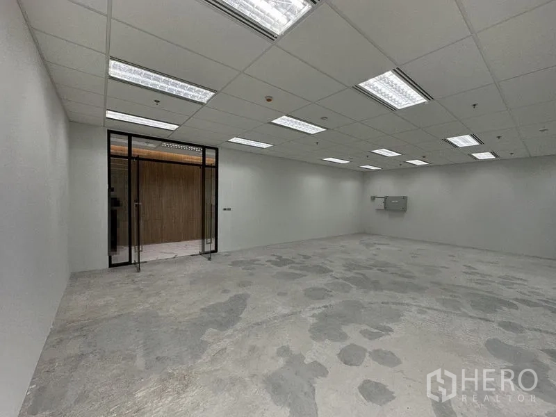 Office Space for rent in Ratchathewi, Bangkok - Glass-door entry to a vacant office with bright ceiling panels and a concrete subfloor ready for fit-out.