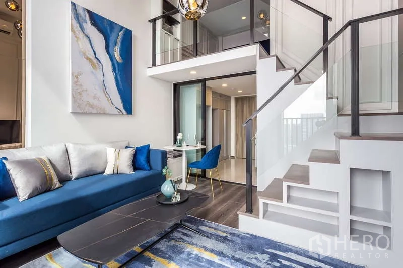 公寓 出租 - 阁楼客厅另一角度，楼梯、夹层与蓝色沙发。