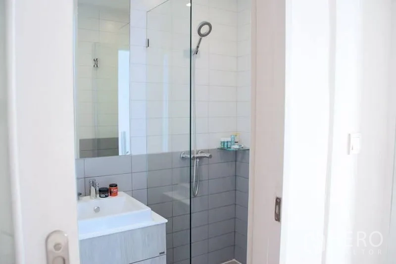 公寓 出售在Phra Khanong, Bangkok - 极简浴室，玻璃淋浴间与白色洗手台。