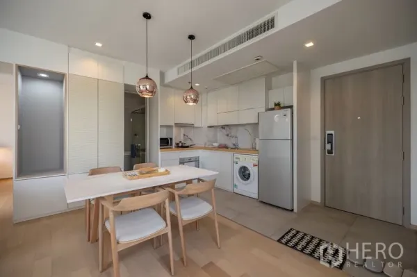 Condominium for rent in Watthana, Bangkok - Modern kitchen with marble backsplash, washing machine and double-door fridge beside the dining table.