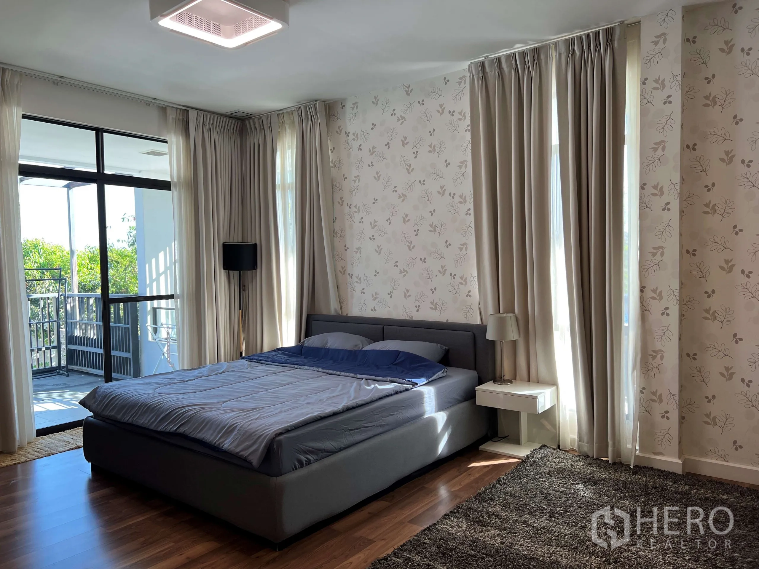 Detached House for rent in Prawet, Bangkok - Spacious master bedroom with balcony access, large windows and soft patterned wallpaper.