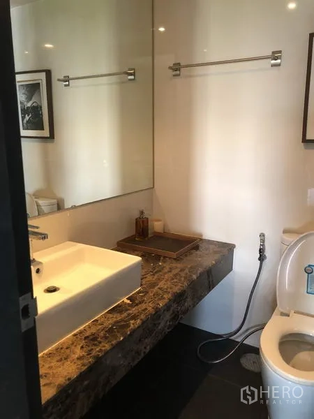 Condominium for rent in Pathum Wan, Bangkok - Marble vanity with vessel sink and large mirror in a contemporary bathroom.