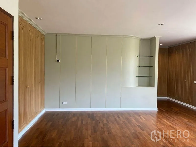 独立式住宅 出租在Watthana, Bangkok - 房间带弧形墙面、展示搁架和木质柜门。