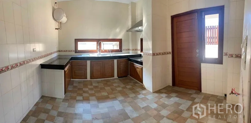 Detached House for sale in Bang Khun Thian, Bangkok - Large Thai kitchen with L-shaped black countertops, wooden cabinets and range hood.