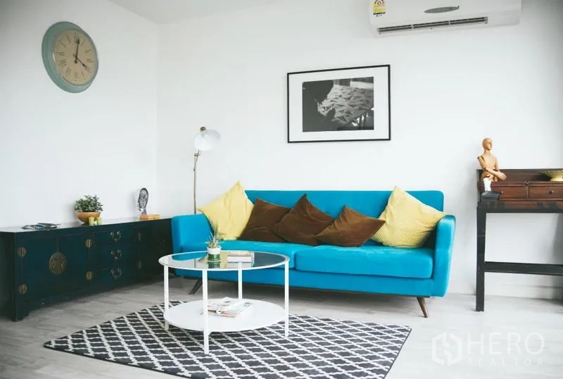 公寓 出售在Phra Khanong, Bangkok - 现代客厅，蓝色沙发、圆形茶几与几何图案地毯。