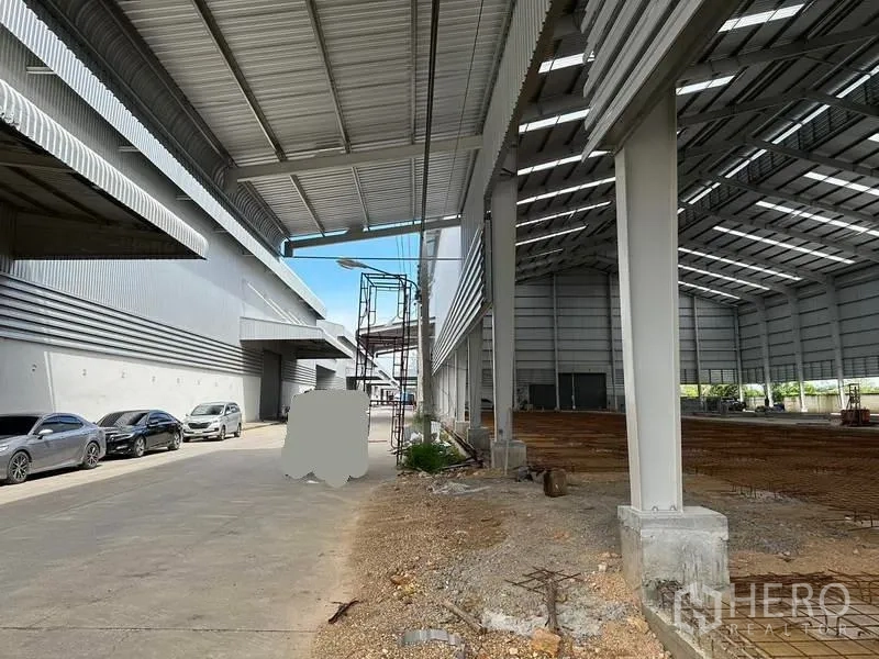 คลังสินค้า ให้เช่าในWang Noi, Phra Nakhon Si Ayutthaya - ชายคาโหลดสินค้ามีหลังคา ข้างอาคารโกดังที่กำลังก่อสร้าง มีรถจอดริมทาง