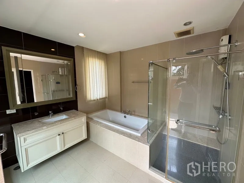 Detached House for rent or sale in Pak Kret, Nonthaburi - Modern bathroom with bathtub, glass shower and long vanity.