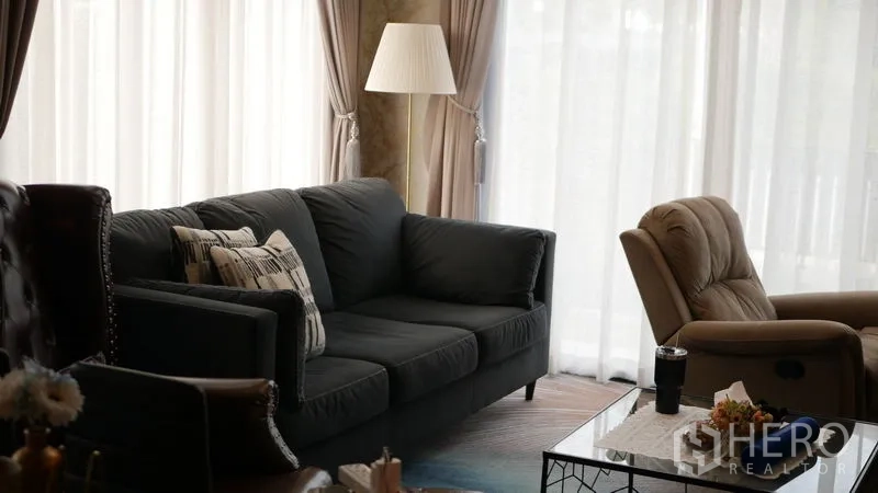 Detached House for rent or sale in Bang Bo, Samut Prakan - Living room with sofa set, tall curtains and natural light.