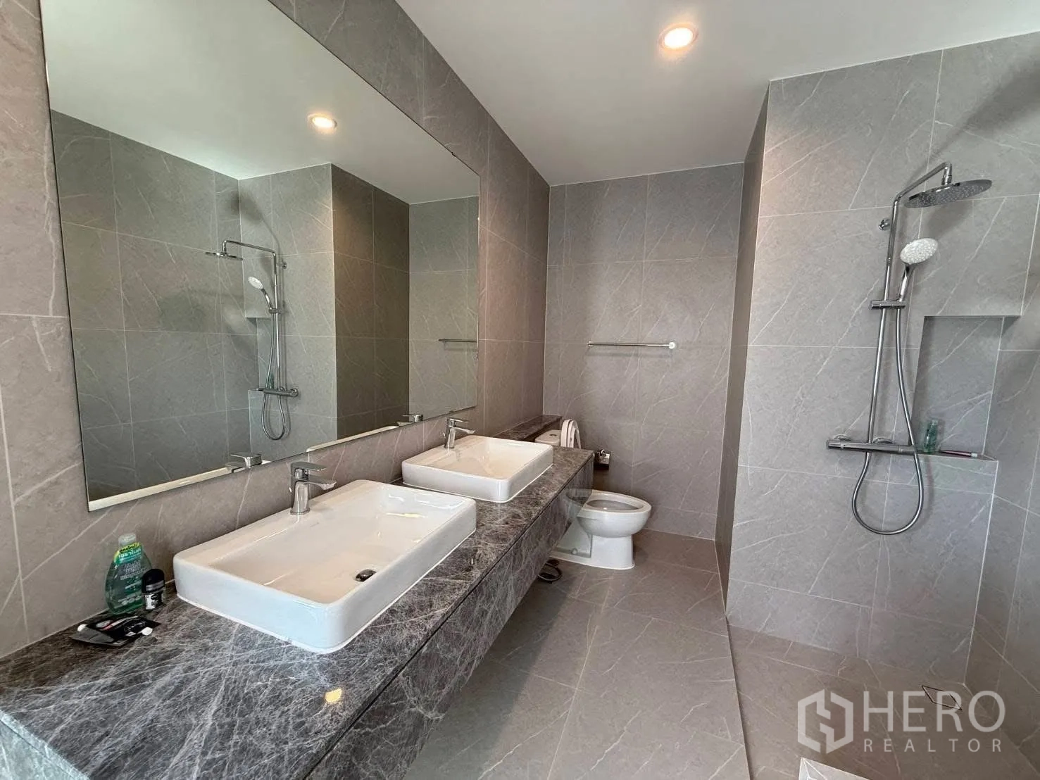 Detached House for rent in Bang Phli, Samut Prakan - Contemporary bathroom with double sinks, a large mirror, gray tiles, a toilet, and dual rain showers.