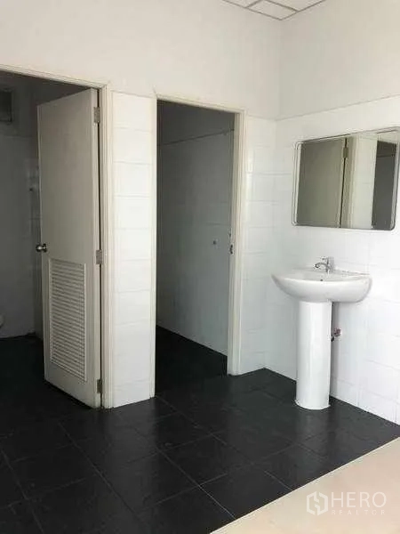 Factory for rent in Samut Prakan - Clean restroom with pedestal sink and tiled walls.