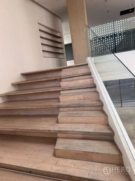 独立商业地产 出租在Khlong Toei, Bangkok - 楼梯平台配玻璃栏杆与穿孔格栅窗，柔和日光过滤。