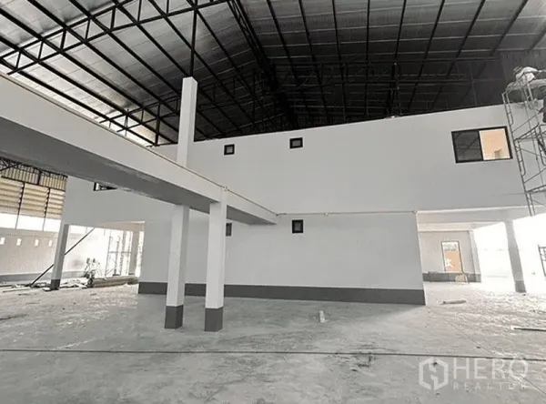 Warehouse for rent in Bang Pakong, Chachoengsao - Open-plan storage hall with mezzanine structure, white columns and metal roof.