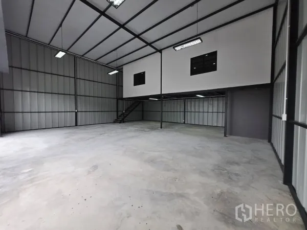 Warehouse for rent - Open industrial hall showing a two-storey office box and staircase with hanging LED lights.