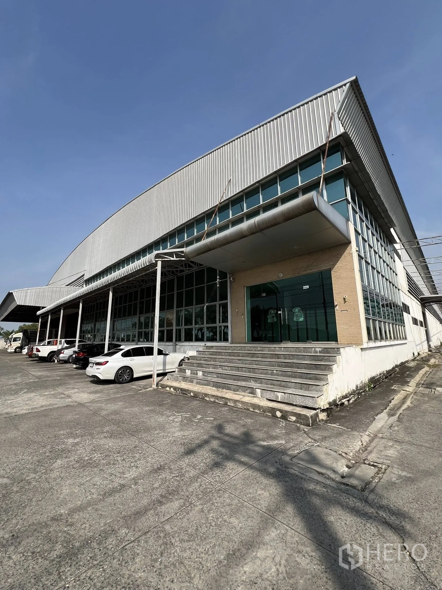 工厂 出租或出售在Sai Noi, Nonthaburi - 工厂正门入口，台阶与雨棚延伸至玻璃立面