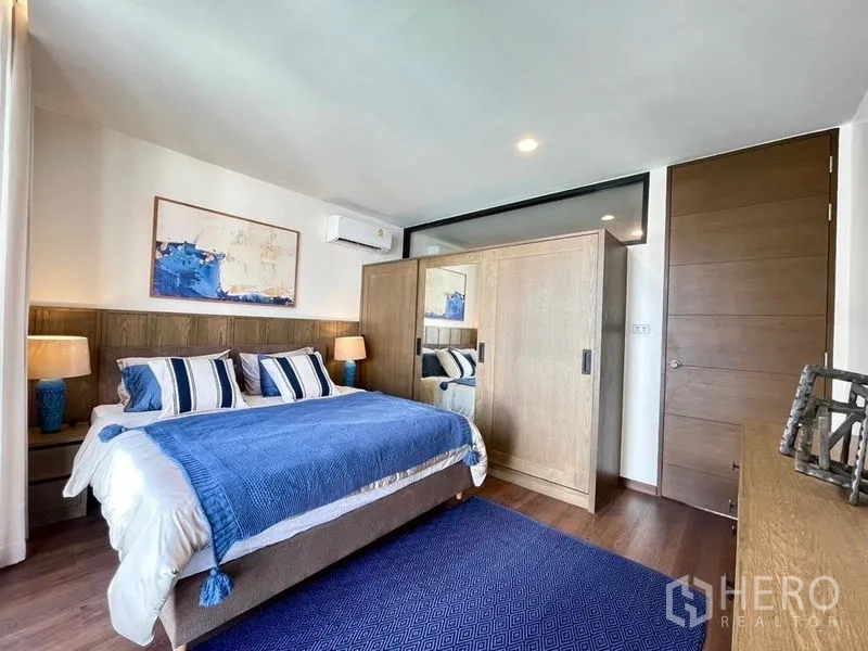 Townhouse for rent - Primary bedroom with blue bedding, wood wardrobe, and large rug.