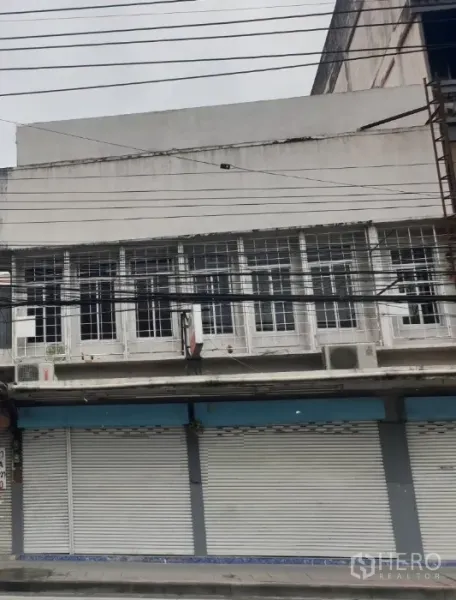 店屋 出租在Watthana, Bangkok - 店屋外立面，金属卷闸门关闭，二层栅格窗与街头电线，临街门面。