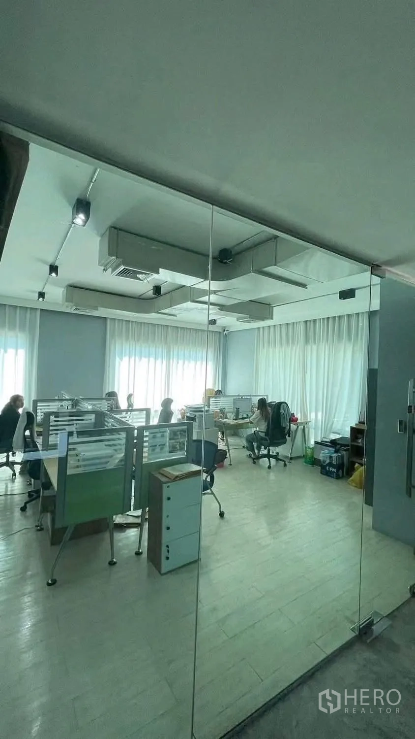 家庭办公室 for rent or sale in Wang Thonglang, Bangkok - 透过玻璃墙看到的办公层，设工位与长帘。