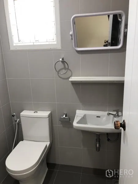 Warehouse for rent in Lat Lum Kaeo, Pathum Thani - Bathroom view with toilet, sink, mirror, and fixtures in a tidy setting.
