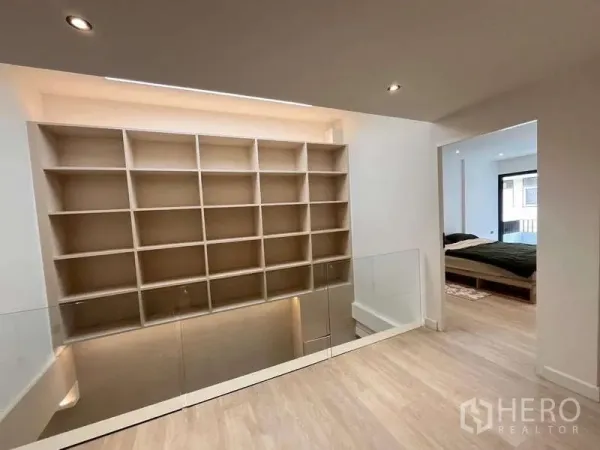 Townhouse for sale in Khlong Toei, Bangkok - Mezzanine with glass balustrade and illuminated shelving leading to a bedroom.