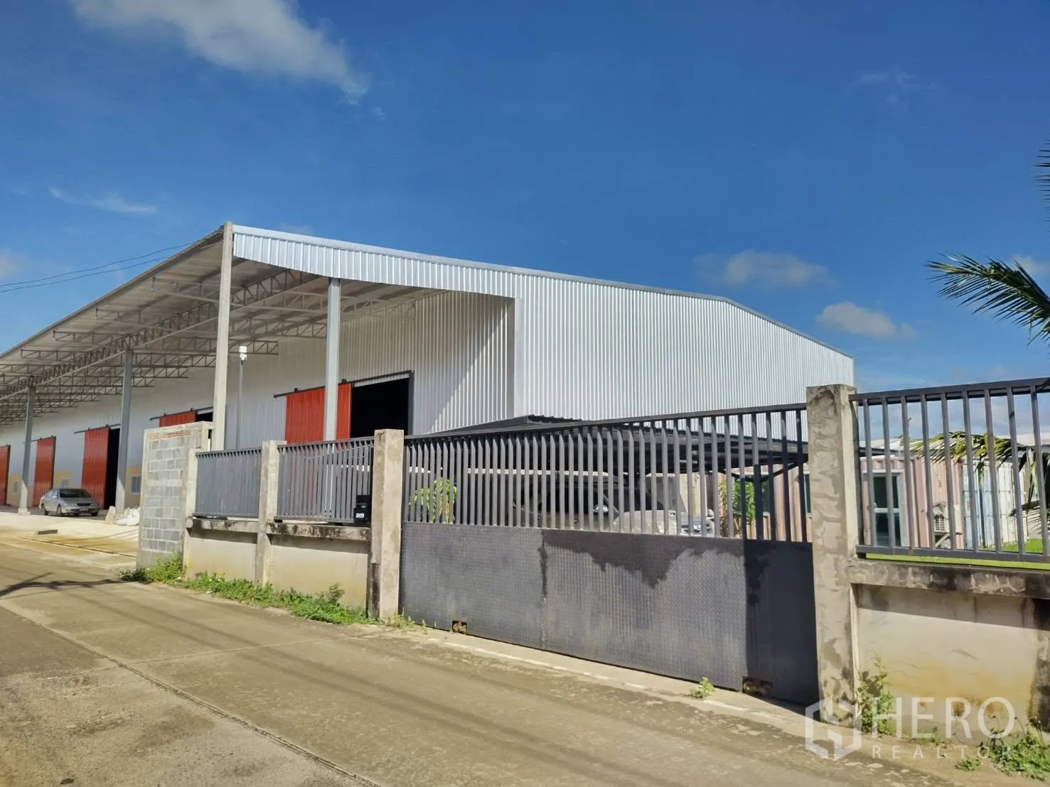โกดัง for rent in Khlong Luang, Pathum Thani - มุมมองมุมของพื้นที่โกดังพร้อมรั้วรอบขอบชิดและประตูทางเข้าติดถนน