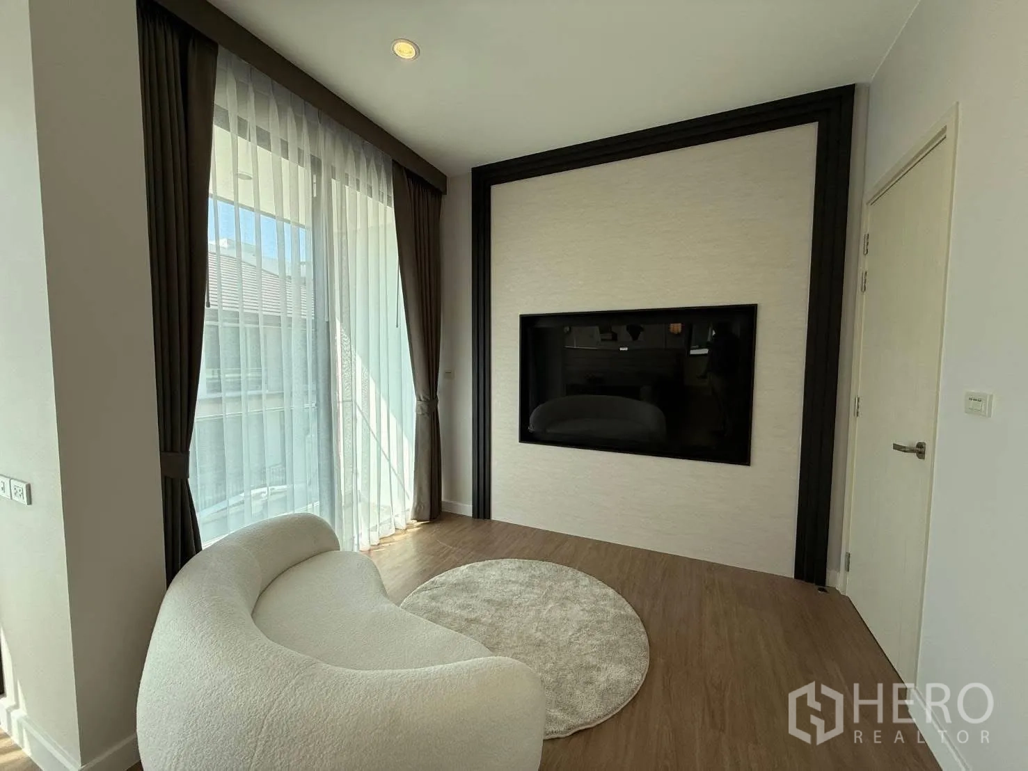 Detached House for rent in Bang Phli, Samut Prakan - Bright sitting area with curved cream sofa, large window drapes, and a built-in TV wall.