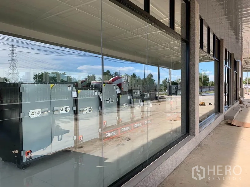 Warehouse for sale in Phra Nakhon Si Ayutthaya - Long row of glass windows reflecting the yard along the sheltered loading bay.