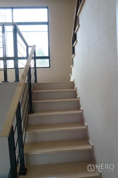 ทาวน์เฮาส์ ให้เช่าในSuan Luang, Bangkok - ภาพระยะใกล้ของบันไดไม้โทนอ่อน ราวเหล็ก ขึ้นสู่ชั้นบน