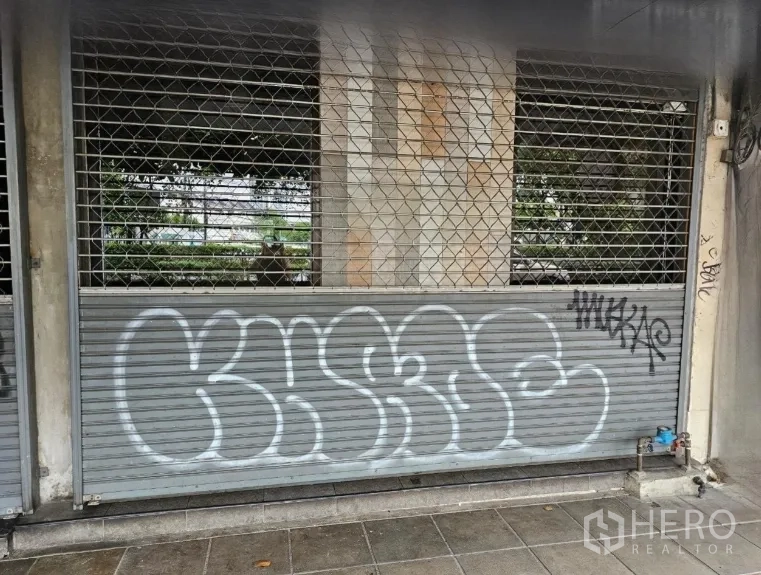 店屋 出租或出售在Watthana, Bangkok - 临街金属卷闸门与安全栅栏，店面前方人行道。
